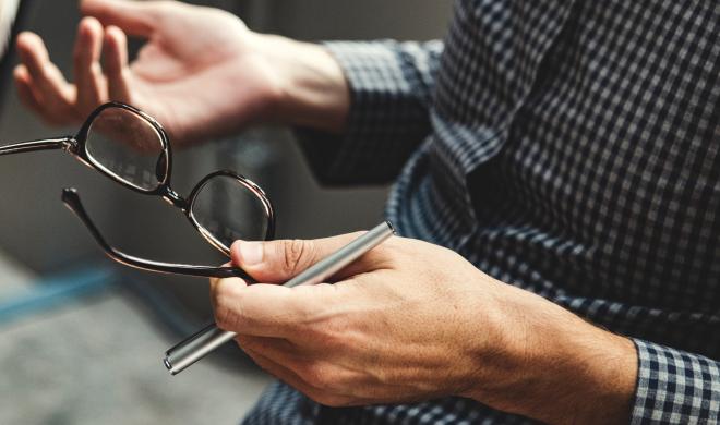 Man gesturing while talking, with glasses.